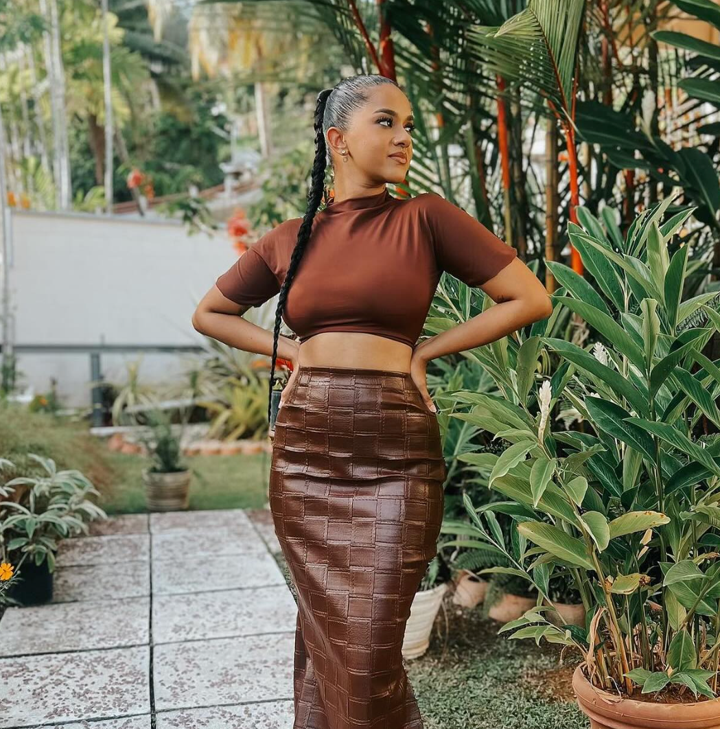 Woman in a brown outfit standing in a garden setting